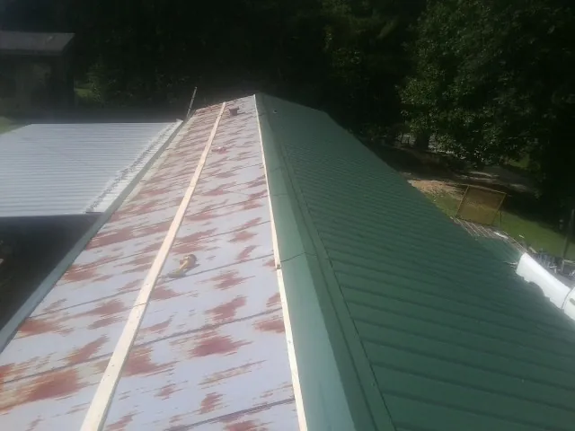 Old rusted panels beside newly installed green metal roofing — Wind Damage Roof Repair by Roofing Brothers in Rosemont
