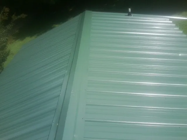 New green metal panels meeting at the ridge of a roof — Flat Roof Repair work by our crew in Rosemont