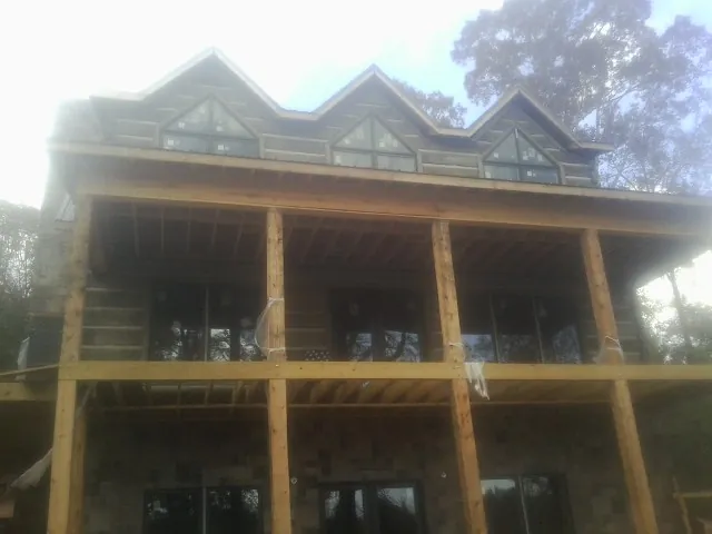 Dormers and porch framing on a large log home under construction — Roof Coating work by our crew in Rosemont
