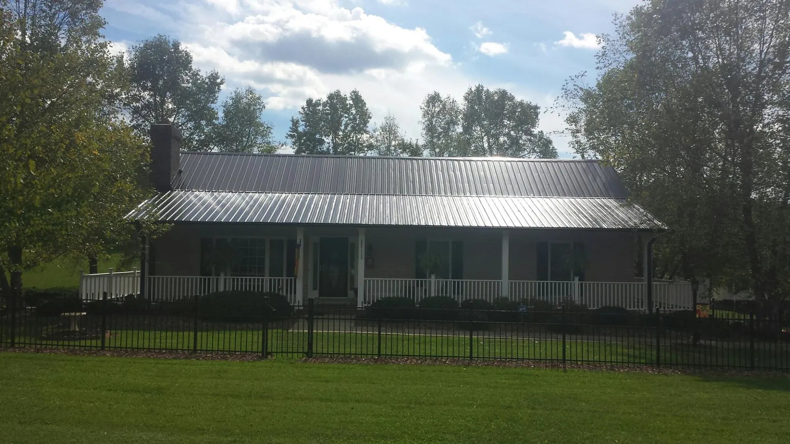 Gray metal roof on a brick ranch with a full width front porch — Gutter Guard Installation work by our crew in Rosemont