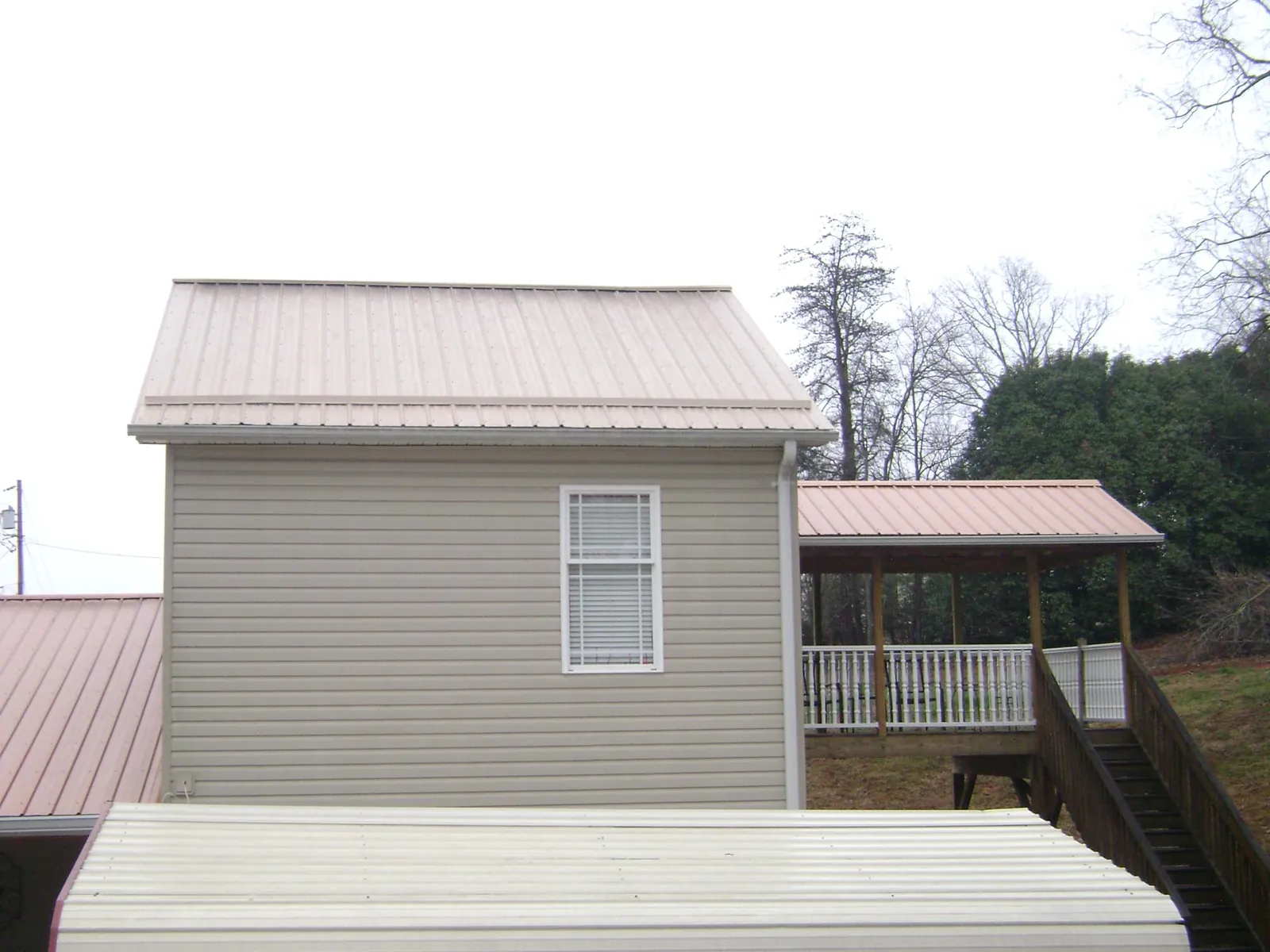 Tan metal roofs on a two story addition and attached porch, from a Roof Replacement job in Rosemont