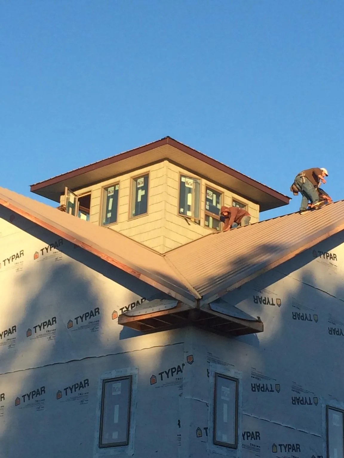 Roofers working around a rooftop cupola on a new metal roof at sunset — Roof Waterproofing in Rosemont by Roofing Brothers